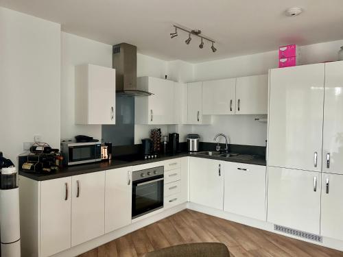 a white kitchen with white cabinets and appliances at My Apartment Brixton - Modern Double Room with En-suite in London