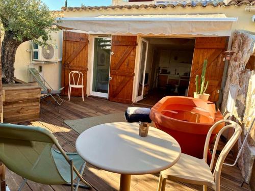 a patio with a table and chairs on a deck at Superbe Maison - Bain Chaud ou Froid & Cinema - Cap d'Agde in Cap d'Agde