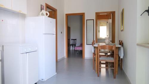 a kitchen with a table and a white refrigerator at Santa Lucia-Park Coppa della Nuvola in Peschici
