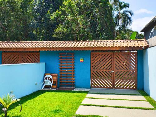 a blue house with a wooden gate and a lawn at Mare de Lua Boraceia in Boracéia