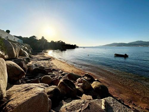 - une plage avec des rochers et un bateau dans l'eau dans l'établissement Casamea - Plage 20m, Vue Mer, Famille, à Porticcio