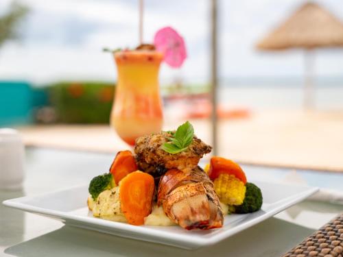 a plate of food with meat and vegetables on a table at Orchid Bay Resort in Corozal