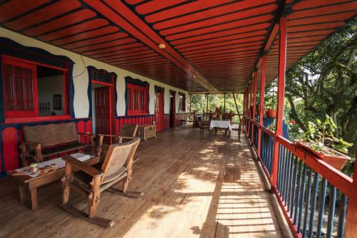 a porch of a house with chairs and a wooden floor at Finca Hotel in Armenia