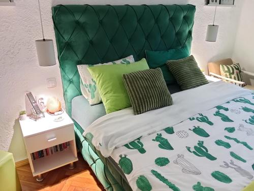 a bed with a green headboard and green pillows at Green Cactus Rooms - unique and cozy house in Senta