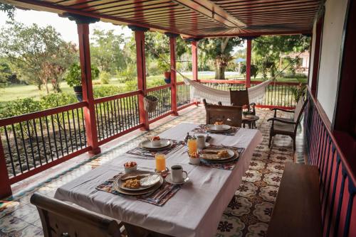 a dining table on a porch with a hammock at Finca Hotel in Armenia