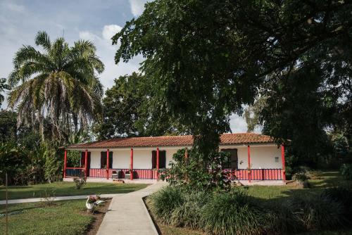 a red and white house with a palm tree at Finca Hotel in Armenia