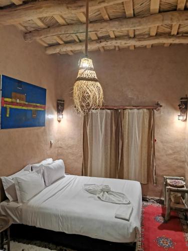 a bedroom with a bed and a chandelier at Maison d'hôte tamatart - Homestay in Kalaat MGouna