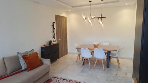 a living room with a table and chairs and a couch at Bel appartement familial résidence sécurisée in Casablanca