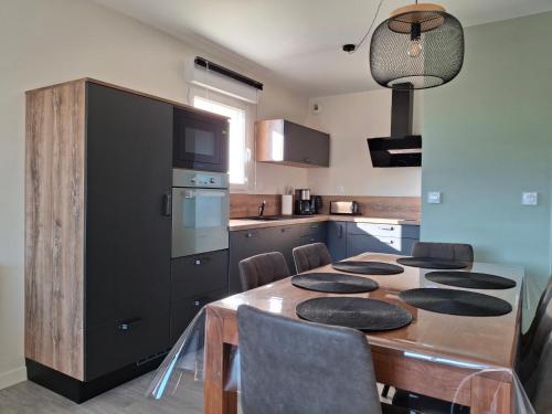 a kitchen with a wooden table and a black refrigerator at Appartement vue étang et port de Dahouët in Pléneuf-Val-André