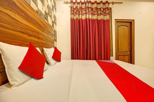 a bedroom with a bed with red and white pillows at Hotel O NR Residency in Banūr