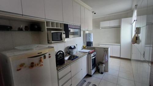 una cucina con mobili bianchi e un frigorifero bianco di Apartamento de 3 quartos a Belo Horizonte