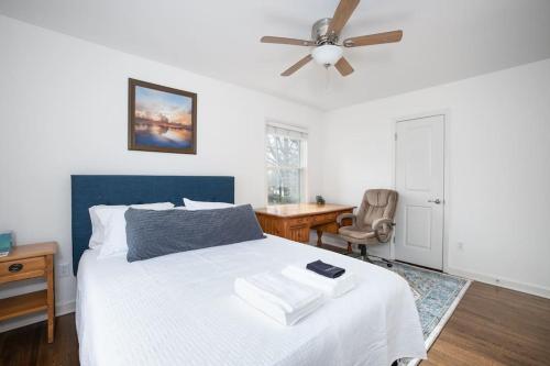 Schlafzimmer mit einem Bett, einem Deckenventilator und einem Schreibtisch in der Unterkunft Beautiful wooded home in Popular SouthPark in Charlotte
