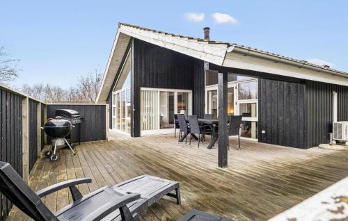 a house with a deck with a grill and chairs at Holiday Home Kronvildtvej Brovst Vi in Brovst