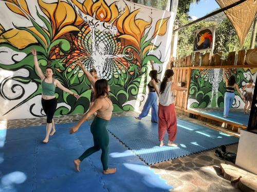 a group of women performing a yoga pose in front of a mural at Unicorn Reborn - Peaceful Rentals in San Marcos La Laguna