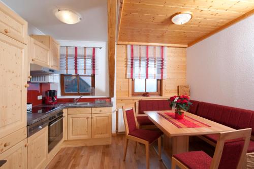 a kitchen with a table and red chairs in a room at Ferienwohnung am Oberrainerhof in Arriach
