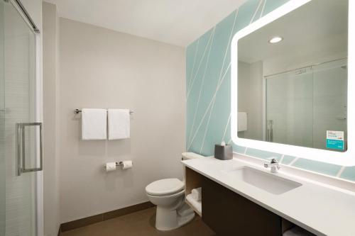 a bathroom with a sink and a toilet and a mirror at avid hotel Plano North by IHG in Plano