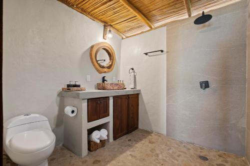 een badkamer met een toilet, een wastafel en een spiegel bij Panchos Paradise Cabaña Parota in Puerto Vallarta