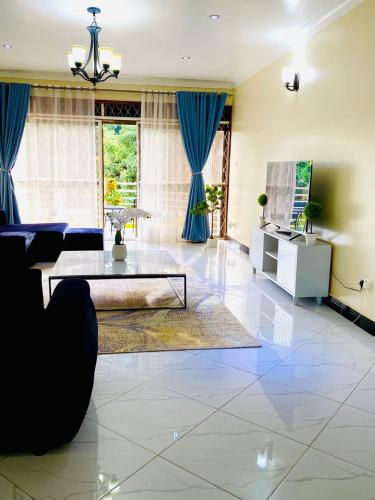 a living room with a table and blue curtains at Hidden beautiful Modern Apartment in Entebbe