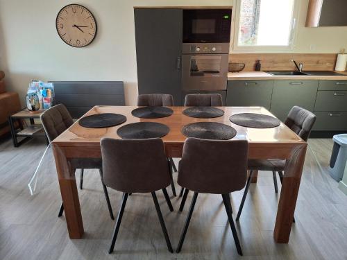 a kitchen with a wooden table with chairs and a clock at Appartement vue étang et port de Dahouët in Pléneuf-Val-André