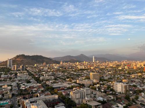 a view of a city with buildings and mountains at Departamento en Ñuñoa, excelente ubicación, frente metro y a pasos del barrio italia in Santiago