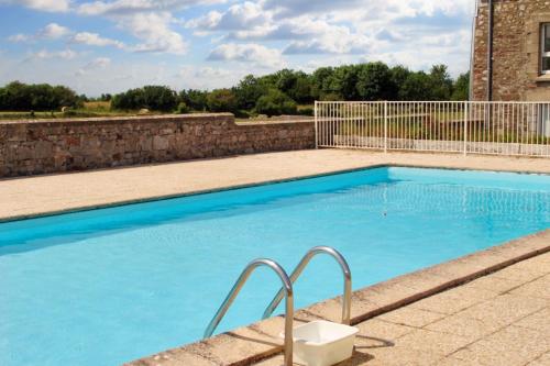 une grande piscine bleue avec un mur en pierre dans l'établissement Appartement familial avec piscine à Montmartin-sur-Mer 54 m², à Montmartin-sur-Mer
