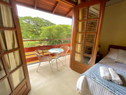 a bedroom with a bed and a table and a balcony at Pousada Portal Sul in Florianópolis