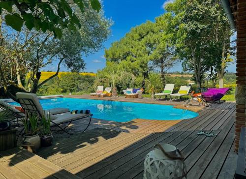 une terrasse en bois avec une piscine et des chaises. dans l'établissement Ferme Le Bacou, à Caraman