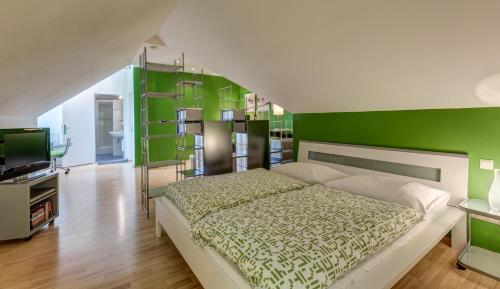 1 dormitorio con una pared verde, 1 cama y TV en Gästehaus Wutschitz, en Antau