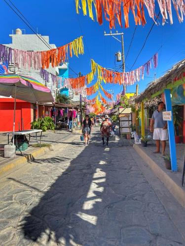 a street with flags and people walking down a street at Casa Faro cerca de la playa in Barra de Navidad
