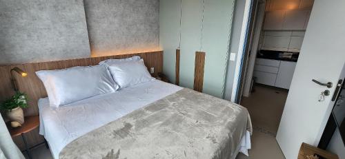 a small bedroom with a bed with white sheets at Parque do Cais - Flats Premium no Recife por Yolo in Recife