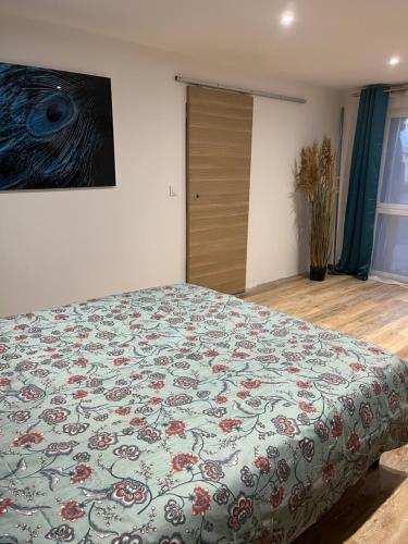 - une chambre avec un lit doté d'une couverture fleurie dans l'établissement Appartement entier, à Corps-Nuds