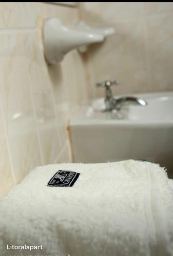 a bathroom with a white towel and a sink at Litoral Apart in Eldorado