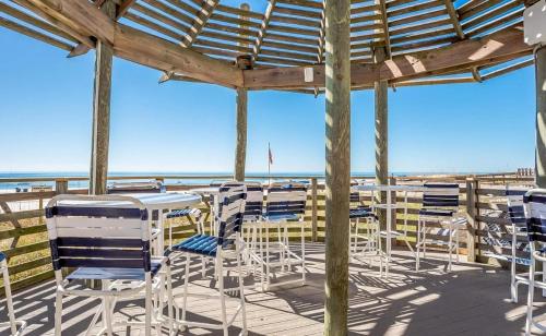 a deck with chairs and tables on the beach at Summer House Unit 904B in Orange Beach