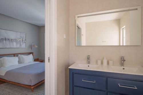 a bedroom with a bed and a sink and a mirror at Bacelos pink house - riverfront with jacuzzi in Soure