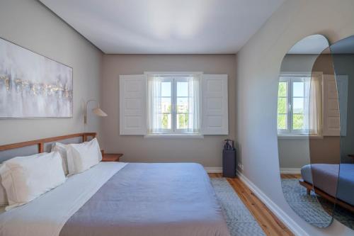 a bedroom with a large bed and two windows at Bacelos pink house - riverfront with jacuzzi in Soure