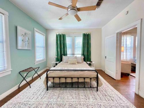 a bedroom with a bed with green curtains and a ceiling fan at Historic & Chic Beaumont Getaway in Beaumont