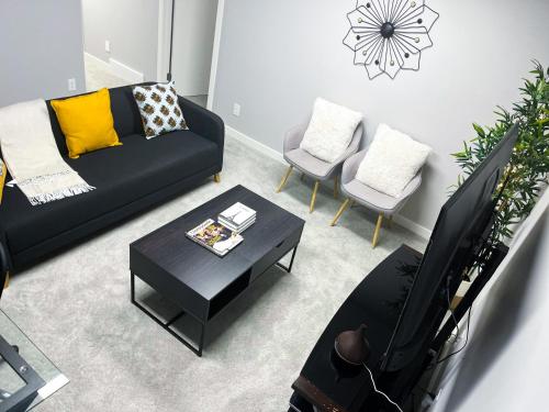 a living room with a black couch and chairs at Modern Basement Suite with Comforts in Winnipeg
