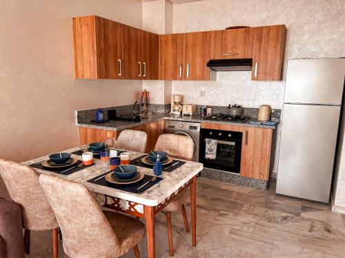 a kitchen with a table with chairs and a refrigerator at Appartement Vue Mer & Coucher de Soleil in Aïn Harrouda