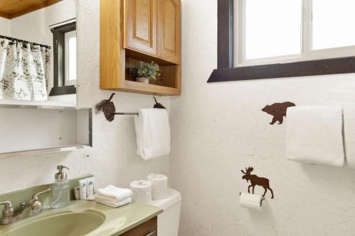 a bathroom with a sink and a toilet with aiger sticker on the wall at Holmes Away from Home by Big Bear Vacations in Sugarloaf