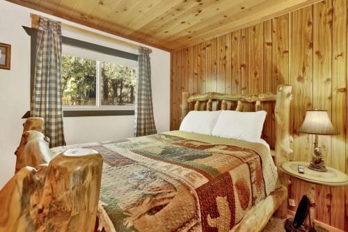 a log cabin bedroom with a bed and a window at Holmes Away from Home by Big Bear Vacations in Sugarloaf