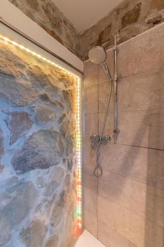 a shower in a bathroom with a stone wall at Sicily Stone Cottage with swimming pool in Graniti