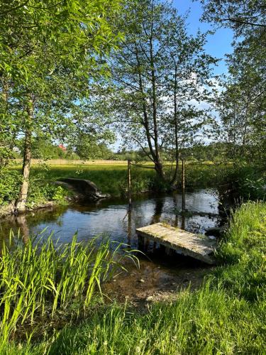 a wooden bridge over a river in a field at Mały domek nad rzeką Słupią in Sulęczyno
