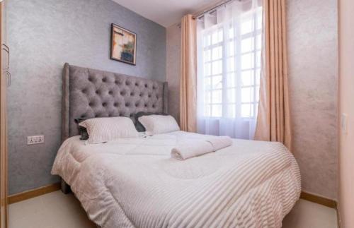 a bedroom with a large bed with a large window at Staycation in Nairobi