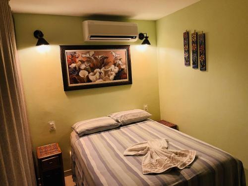 a small bedroom with a bed and a fan at Pousada Flor de Alecrim in Goiana
