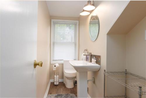 a bathroom with a sink and a toilet and a window at Stunning Apt w Rooftop & Game Room - Sleeps 10 in Pittsburgh