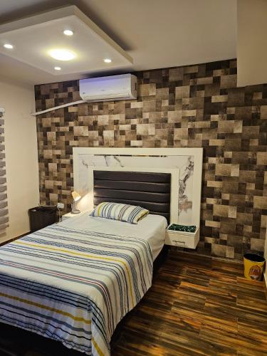 a bedroom with a bed and a brick wall at Quadro apartment in Amman