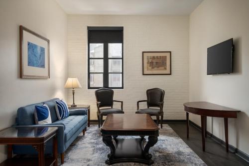 a living room with a couch and chairs and a tv at Le Richelieu Hotel in the French Quarter in New Orleans