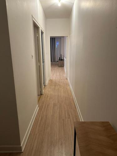 un couloir vide d'un appartement avec des murs blancs et du parquet dans l'établissement Appartement de 60 m2 au centre ville de morez, à Morez