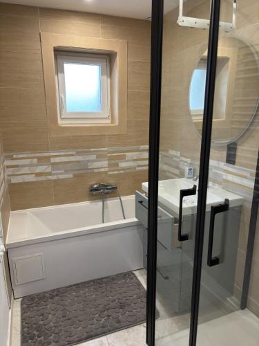 une salle de bain avec une baignoire, un lavabo et un miroir dans l'établissement les dunes proche plage jardin, à Urville-Nacqueville