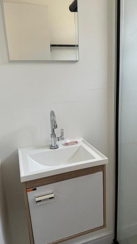a bathroom with a white sink and a mirror at House Box 04 in Itapema